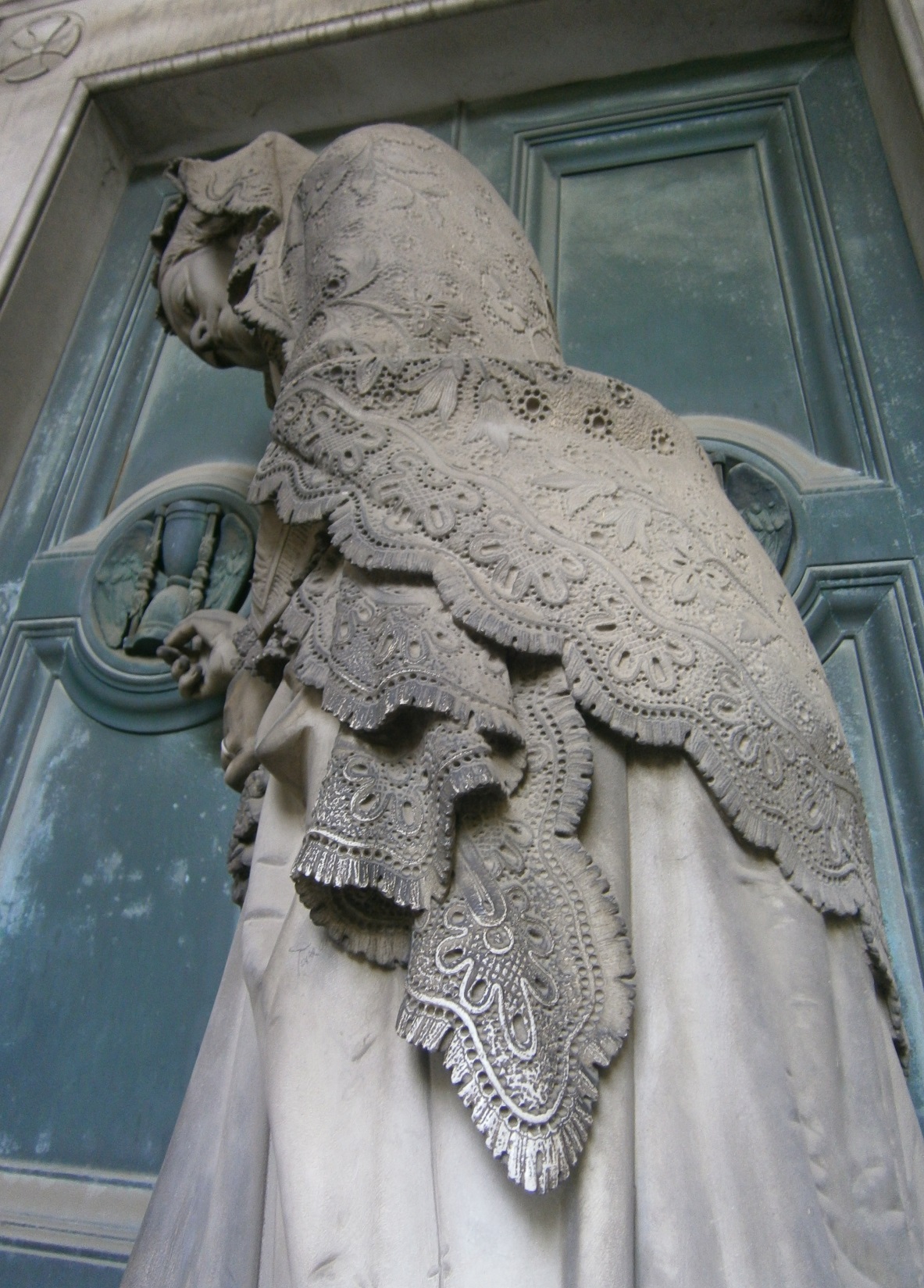 Tomba Badaracco – Porticato Inferiore, donna vestita a lutto davanti alla porta della tomba del marito